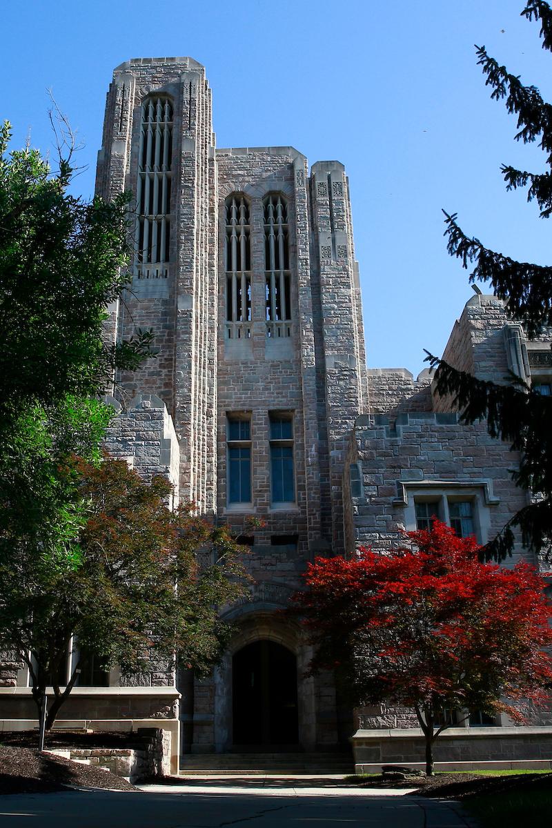 limestone building with trees in reds and greens in front